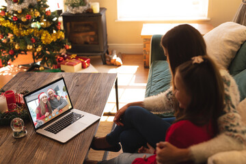 Caucasian mother and daughter in santa hat on christmas laptop video call with friends couple