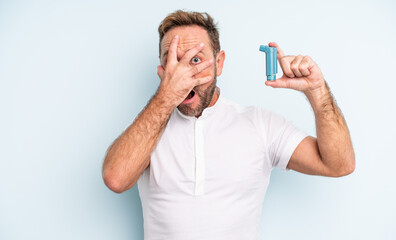 middle age handsome man looking shocked, scared or terrified, covering face with hand. asthma...