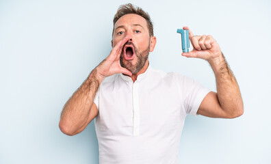 middle age handsome man feeling happy,giving a big shout out with hands next to mouth. asthma...
