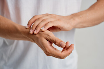 a man in a white t-shirt holding a hand pain in the wrist