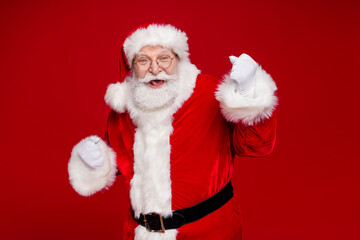 Photo of impressed lucky man pensioner dressed santa claus costume rising fists smiling isolated red color background