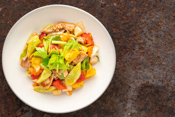 Moo Pud Preaw Wan, Thai food, sweet and sour sauce stir fried with pork, pineapple, tomato, cucumber, onion topped with celery in ceramic plate on rusty texture background, top view