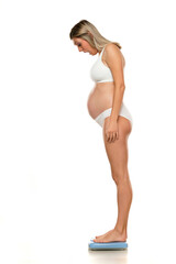 Fototapeta premium Young nervous pregnant woman standing on a scale