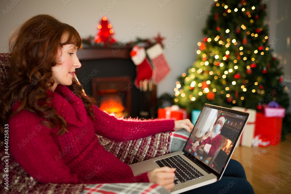 Canvas Prints Caucasian woman on laptop christmas video call with santa in face mask