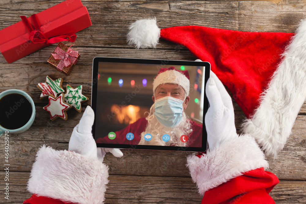 Canvas Prints Hands of santa claus on tablet christmas video call with santa wearing face mask