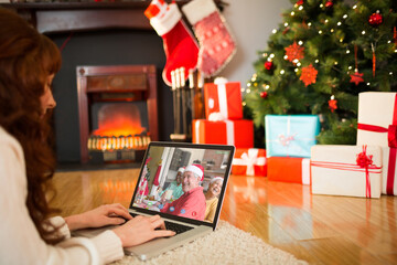 Caucasian woman on laptop christmas video call with smiling family in santa hats