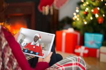 Naklejka na ściany i meble Caucasian woman on tablet christmas video call with smiling santa claus