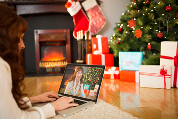 Naklejka na ściany i meble Caucasian woman on laptop christmas video call with smiling female friend