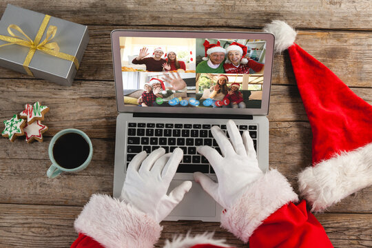 Hands of santa claus on laptop christmas video call with smiling friends