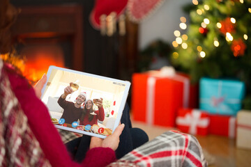 Obraz na płótnie Canvas Caucasian woman making tablet christmas video call with smiling couple raising glasses