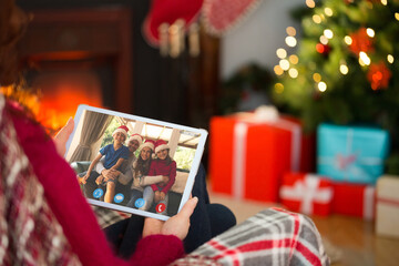 Naklejka na ściany i meble Caucasian woman making tablet christmas video call with smiling caucasian family