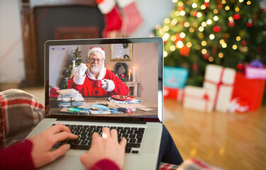 Caucasian woman on christmas laptop video call with caucasian santa claus