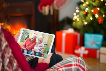 Caucasian woman on christmas tablet video call with caucasian senior couple