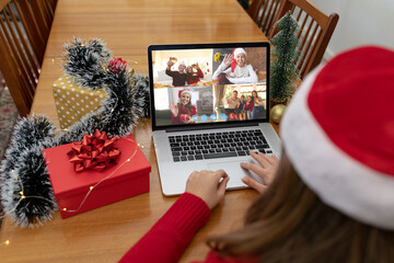 Caucasian woman on christmas laptop video call with diverse group of friends