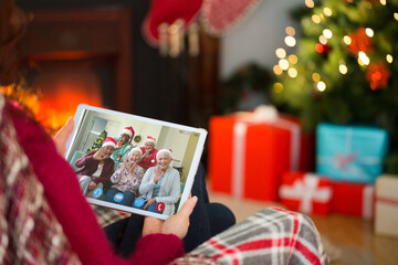 Caucasian woman on christmas tablet video call with diverse group of friends