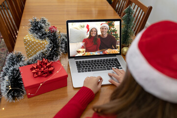 Caucasian woman on christmas laptop video call with caucasian couple