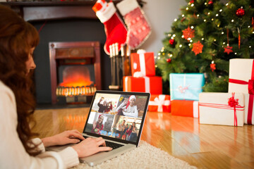 Caucasian woman on christmas laptop video call with diverse group of fiends