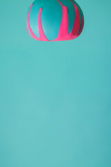 Blue pumpkin turned upside down with contrast pink dripping paint on vibrant turquoise background. Creative vegetable food concept. Minimal Thanksgiving or Halloween layout with blank copy space.