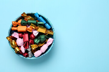 Candies in colorful wrappers on light blue background, top view. Space for text