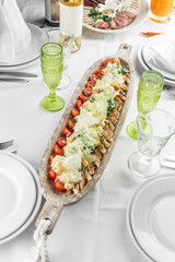 Chicken Caesar salad with bread and tomatoes in wooden boat on the table