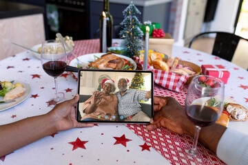 Hands of african american couple holding tablet with african american senior couple on screen