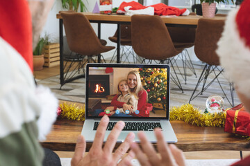 Naklejka premium Caucasian couple in santa hat on christmas video call on laptop with family