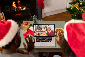 African american couple in santa hats on christmas video call with family