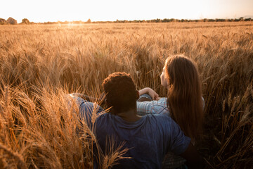 Naklejka na ściany i meble Hugging couple meeting sunset in a wheat field