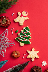 Decorated Christmas gingerbread cookies with decorations on red table background.