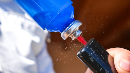 filling, refilling a lighter with butane with the liquid gas escaping clearly visible and frozen on the stem of the gas dispenser