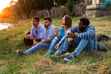 The group of young diverse people eating fastfood on nature