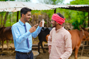 Obraz premium Young indian agronomist or animal doctor collecting milk sample at dairy farm