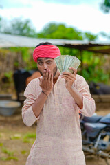 Happy Indian farmer showing money at home.