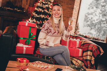 Obraz na płótnie Canvas Photo of excited sweet mature woman wear print sweater smiling celebrating new year drinking champagne indoors house home room