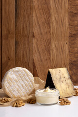 Fototapeta na wymiar Vertical image of set of delicious fresh cheese,walnut on the white table against wooden background.Empty space