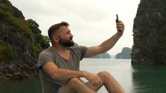 Young man taking selfie photo during cruise in Ha Long bay