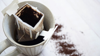 マグカップにセットされた捨てマグペーパードリップコーヒーと散らばるコーヒーの粉