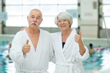 elderly couple by pool with thumbs up