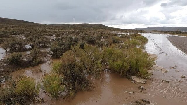Panning view over flooded desert in Wyoming after heavy rainstorm as mud flows through the sagebrush.