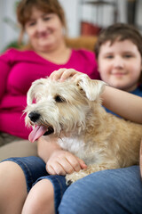 A child holds a shaggy dog in his lap. The dog has its mouth open and its tongue sticking out.