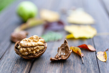 Texture background with walnut, autumn yellow and brown autumn leaves on wooden surface. Autumn leaf fall. Natural autumn background.