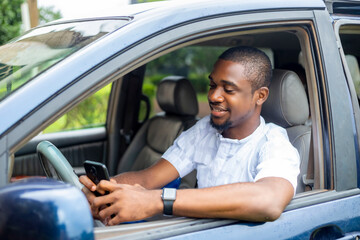 young black african handsome male using mobile phone while driving his car