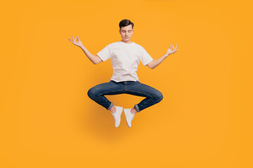 Fototapeta na wymiar Portrait of funny peaceful dreamy guy jump meditate harmony concept on yellow background