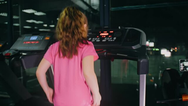 Fit Athletic Baby Girl Running on the Treadmill, Doing Her Fitness Exercise. Cute Children Actively Training in Modern Gym. Sports Child Workout in Running track Fitness Center. Slow Motion