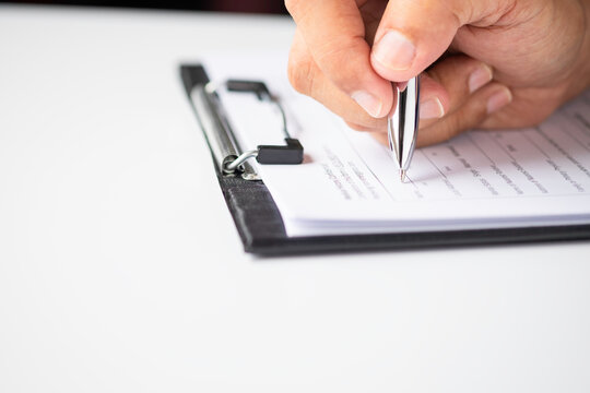 Image of Hand using writing pen with questionnaire or paperwork survey question filling in business company personal information form checklist document.