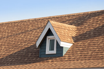 Roof shingles with garret house on top of the house. dark brown asphalt tiles on the roof...