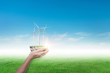 Hands holding wind turbine on grass field against blue sky background. ecology concept