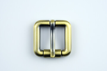Square bronze  buckle with a flat tongue on a white background. Metal hardware for the manufacture of belts. High quality sewing accessories. Bag buckle top view.