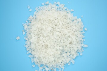 Fototapeta na wymiar White sea salt grain top view. Coarse salt on a blue background. Pile of natural salt on color background