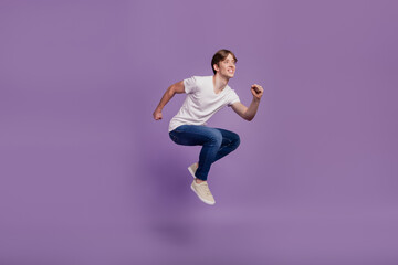 Fototapeta na wymiar Full size profile side photo of young man have fun jump go run look empty space fast isolated on violet color background